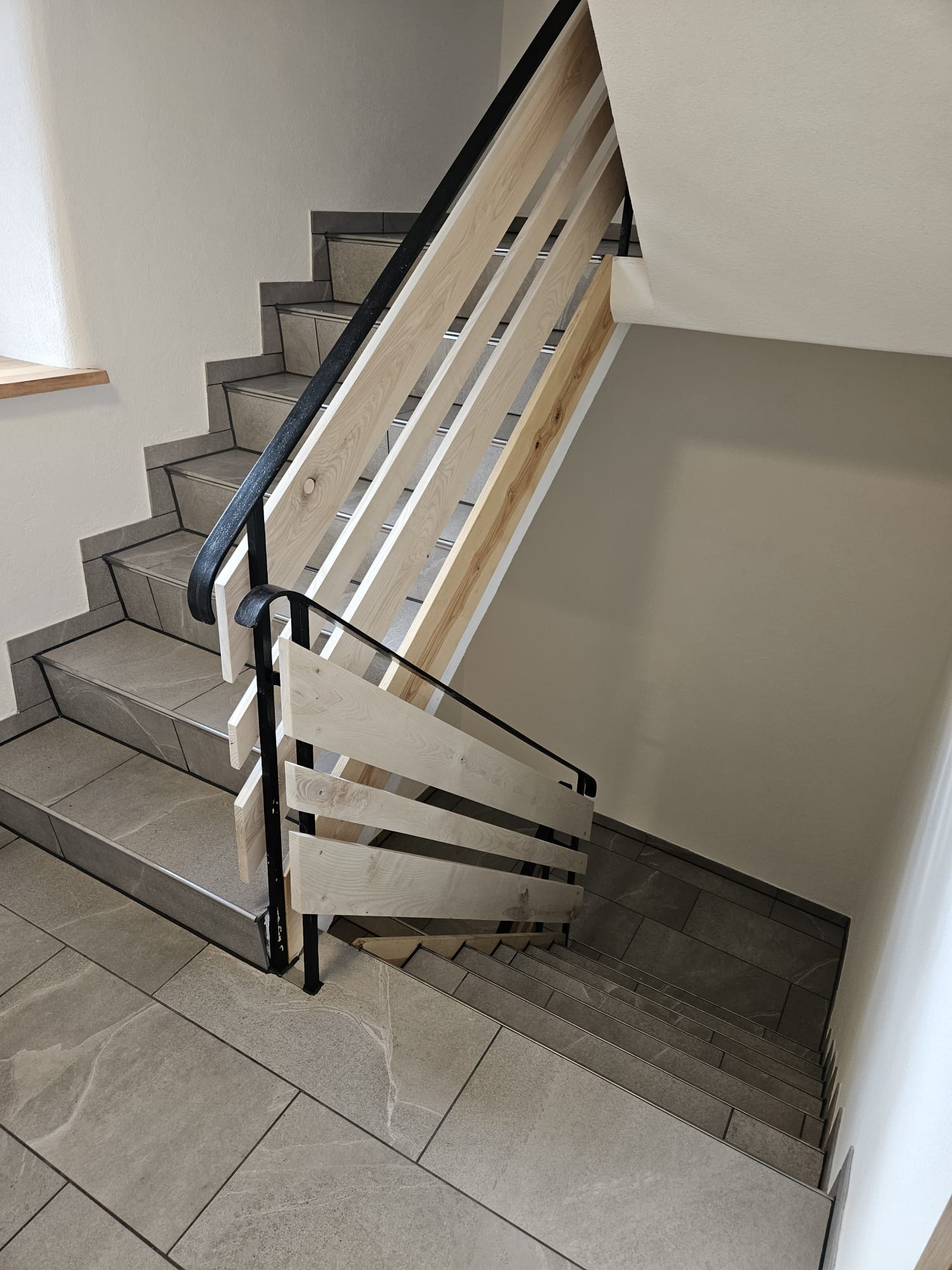 Treppe mit grauen Feinsteinzeug-Stufen und schwarzem Geländer